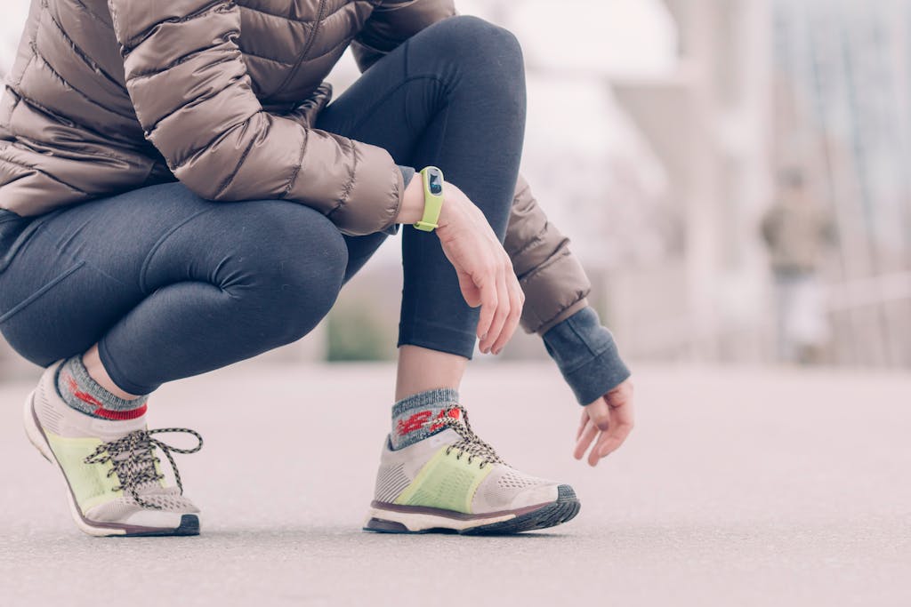 Outdoor shot of a person crouching, showcasing vibrant sneakers and a winter outfit.
